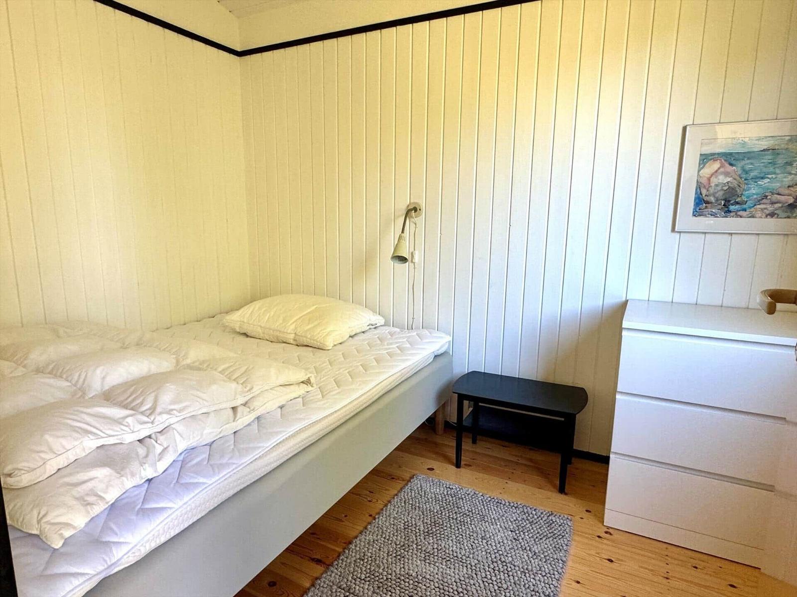 Schlafzimmer mit Bett, Nachttisch und Schrank an Holzwand