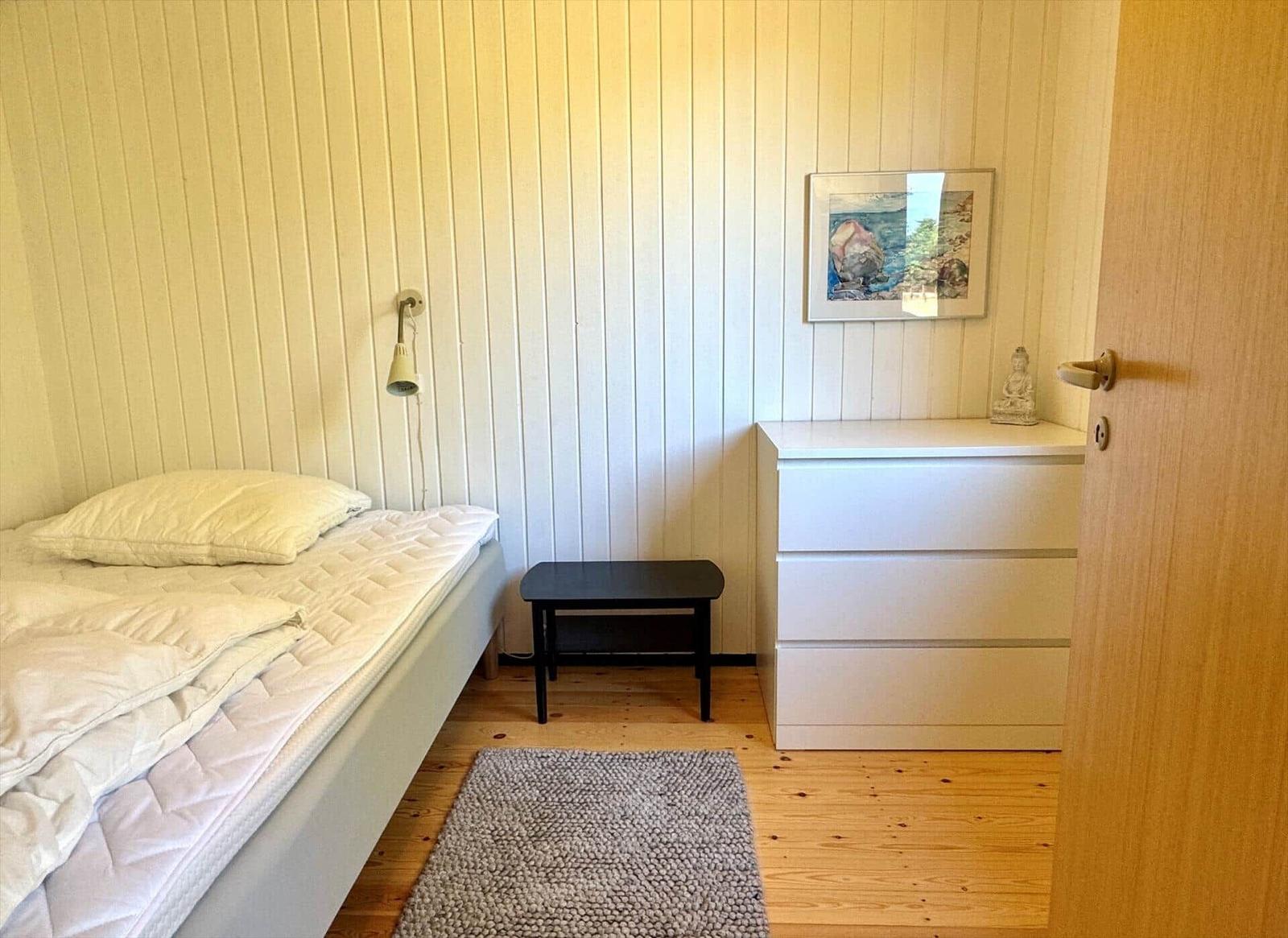 Schlafzimmer mit Bett, Schrank, Nachttisch und Wandbild.