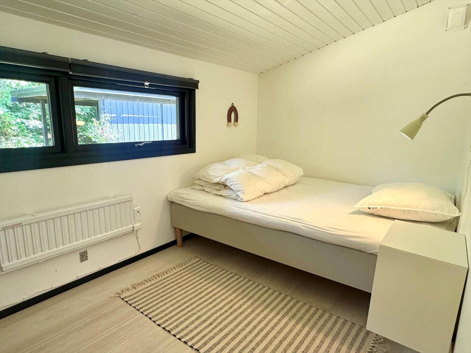 Ein Schlafzimmer mit Bett, Fenster und Teppichboden.