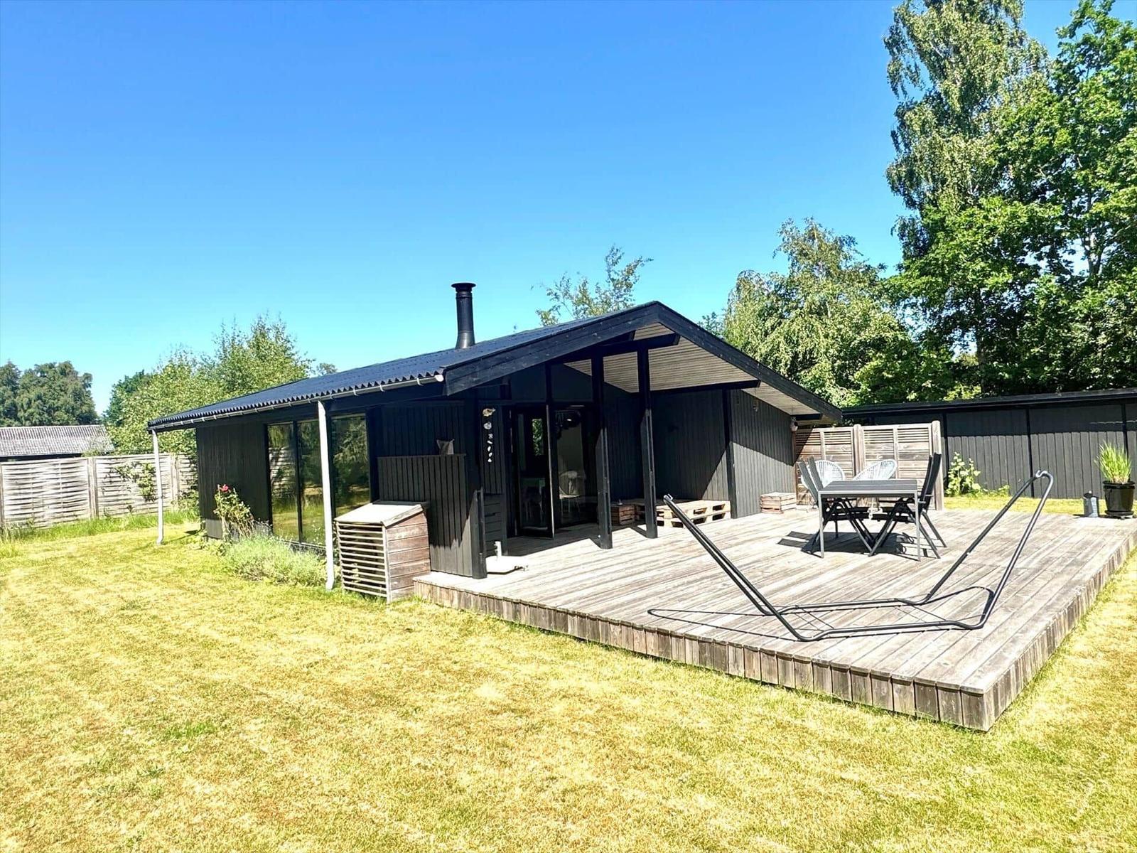 Moderne Hütte mit Terrasse, Sitzgelegenheiten und Garten. Holzterrasse mit Liege.