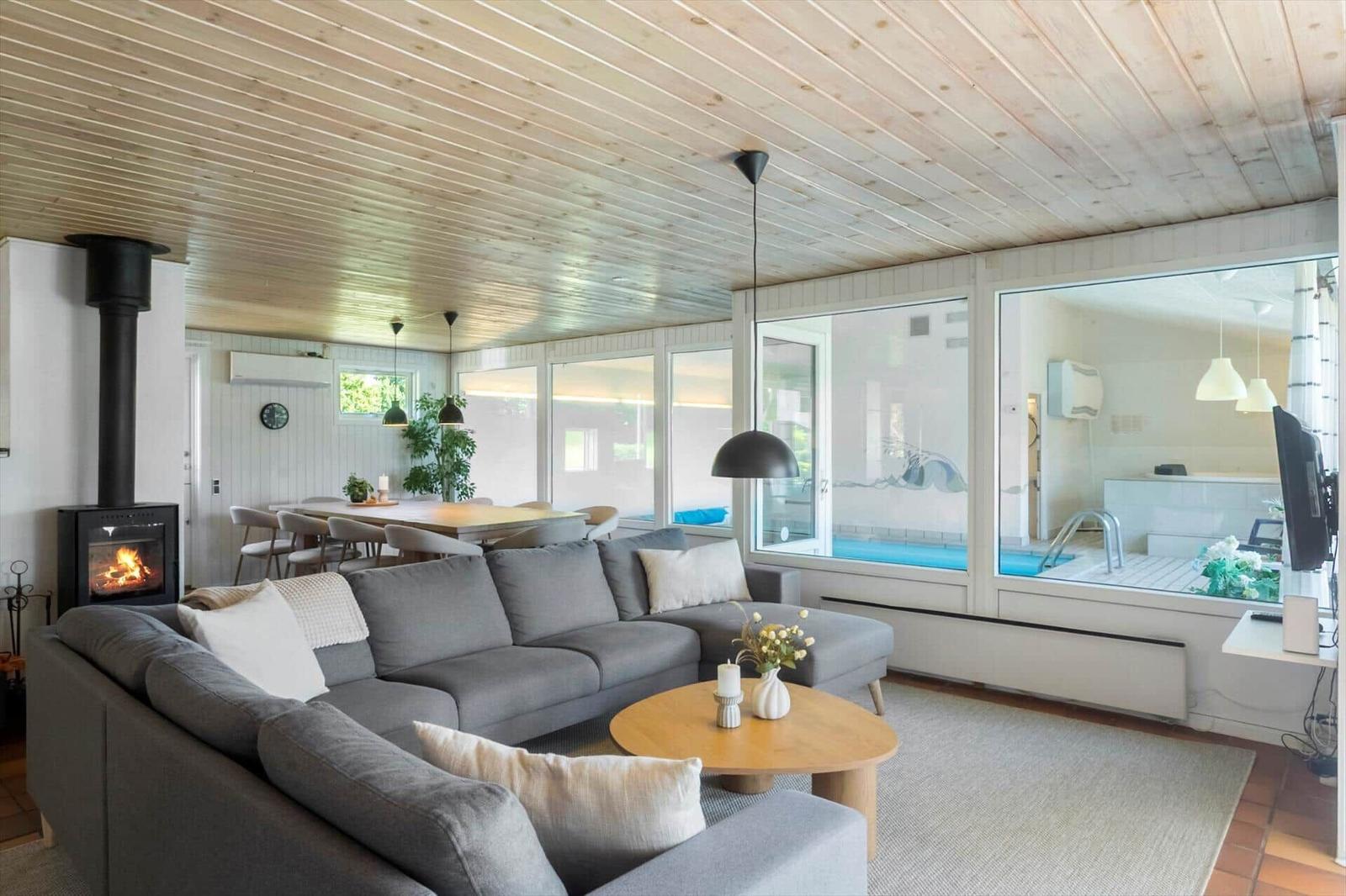 Wohnzimmer mit Sofa, Kamin und Blick auf Pool