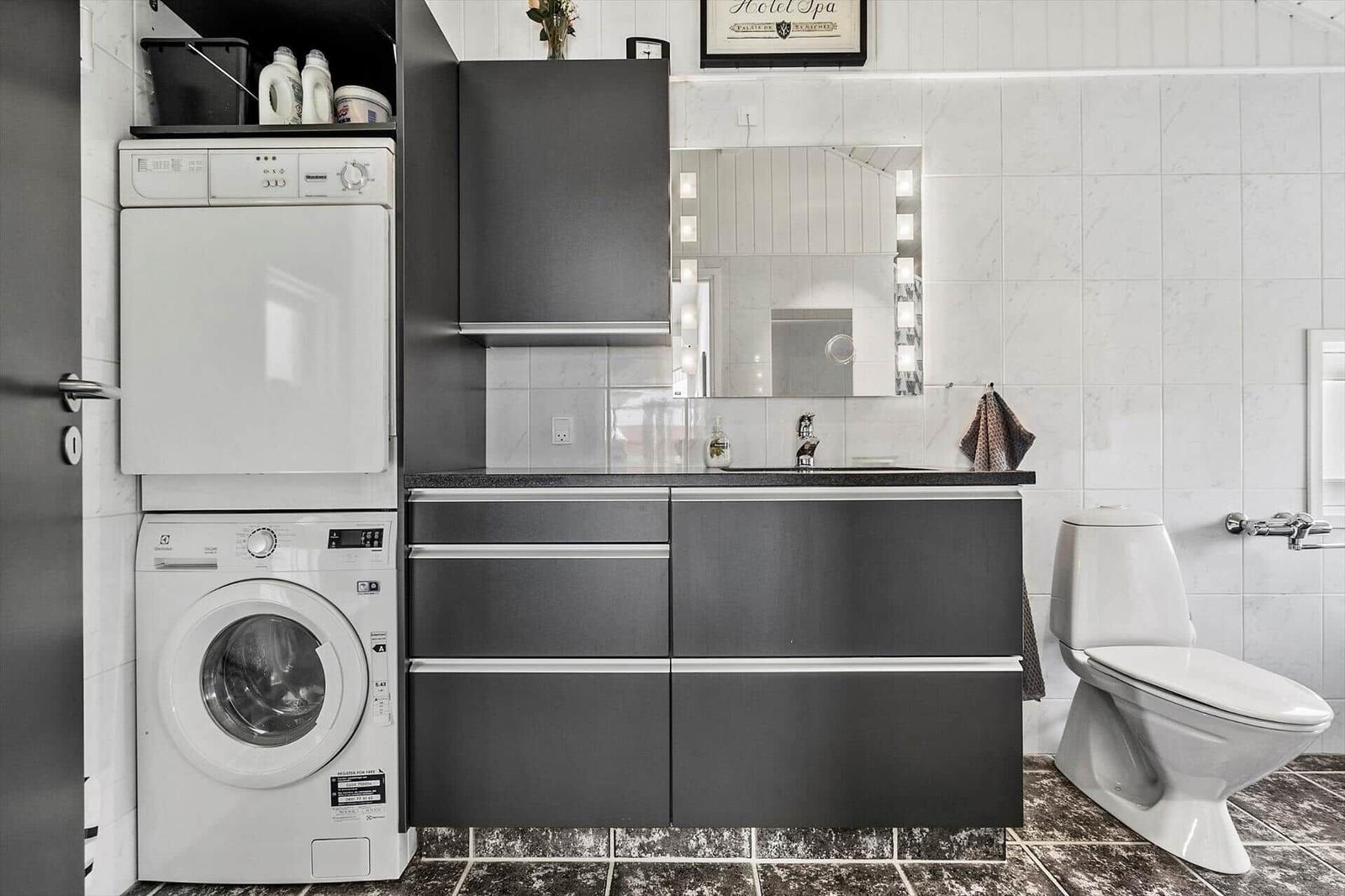 Badezimmer mit Waschmaschine, Spiegelschrank und Toilette