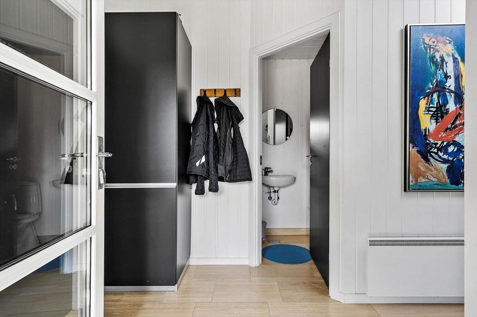 Eingangsbereich mit Garderobe, Wandbild und Blick in das Bad.