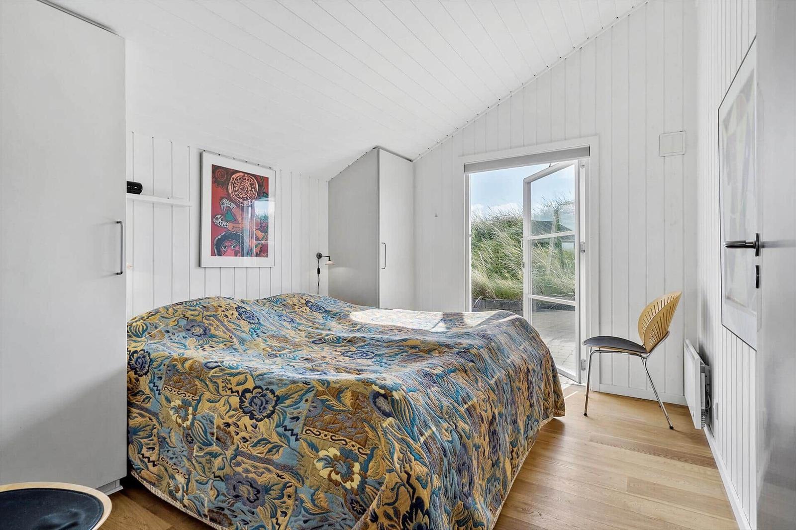 Schlafzimmer mit Bett, Schrank und Tür zum Außenbereich.