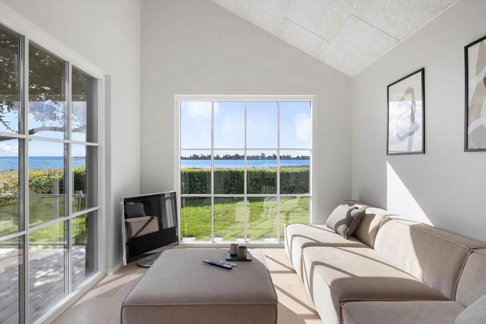 Wohnzimmer mit Sofa, Fernseher und Blick auf den See.
