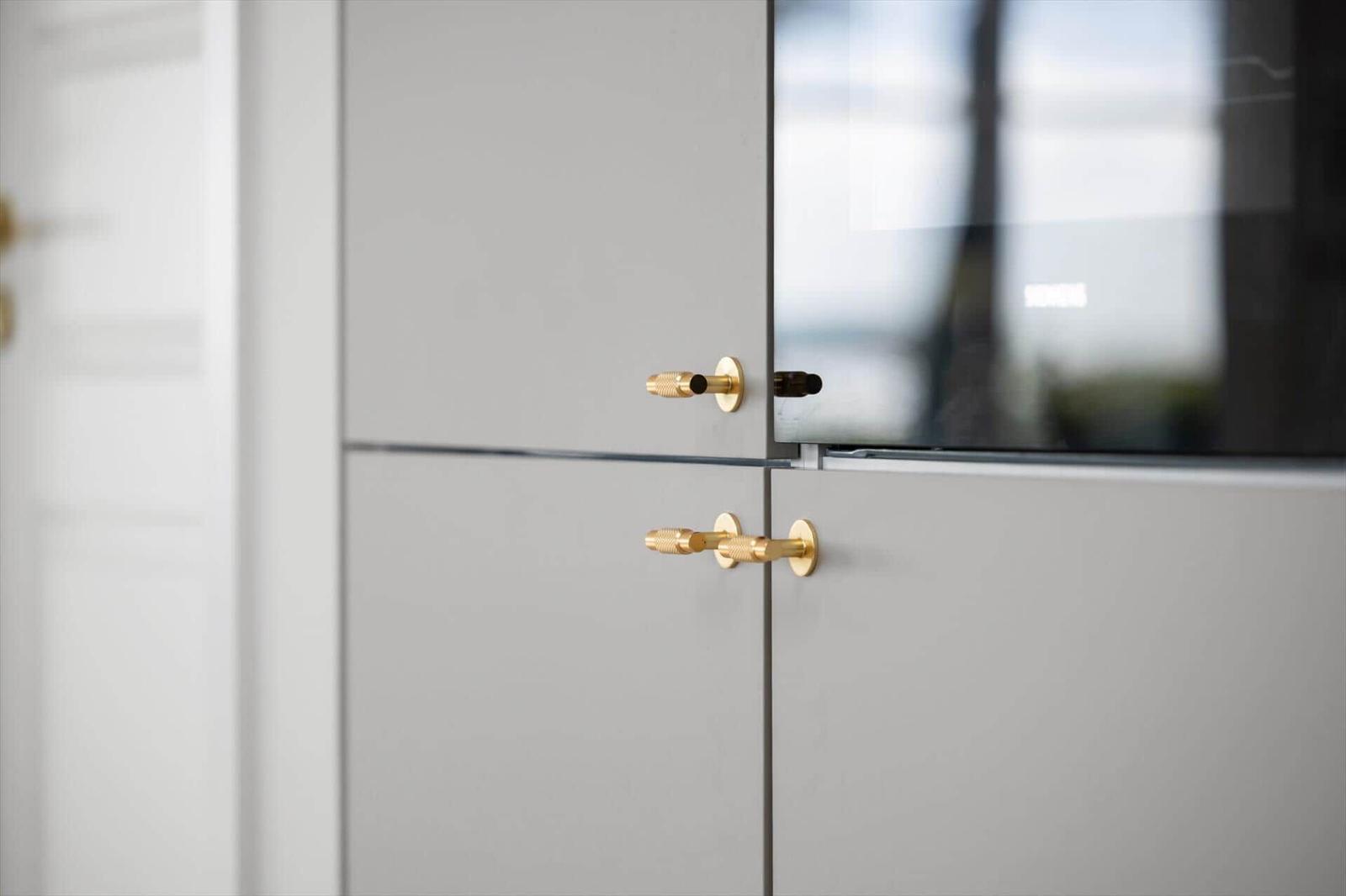 Moderne Schrankfronten mit goldenen Griffen und Glasfront.