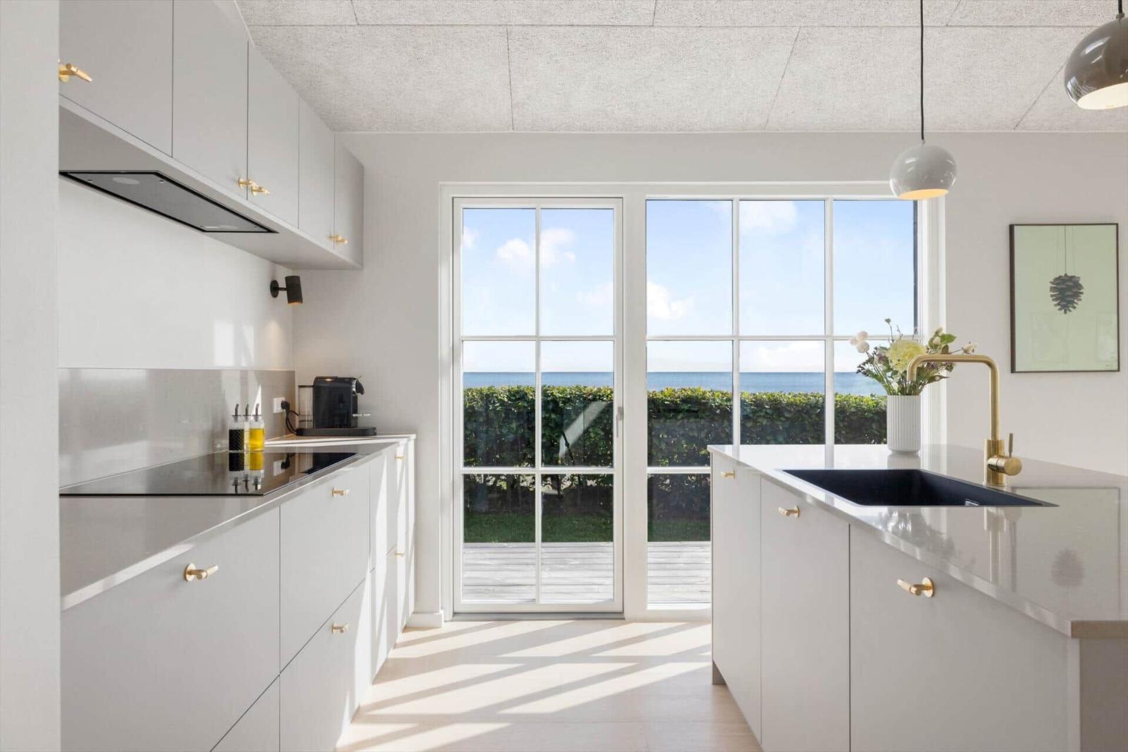 Moderne Küche mit Blick auf den Ozean und grüne Hecke.