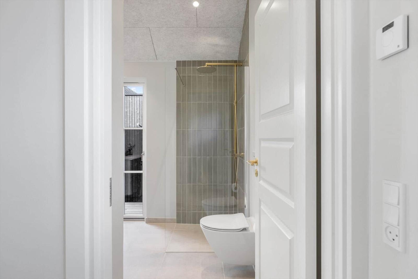 Badezimmer mit Dusche, Toilette und Fenster zur Außenseite.