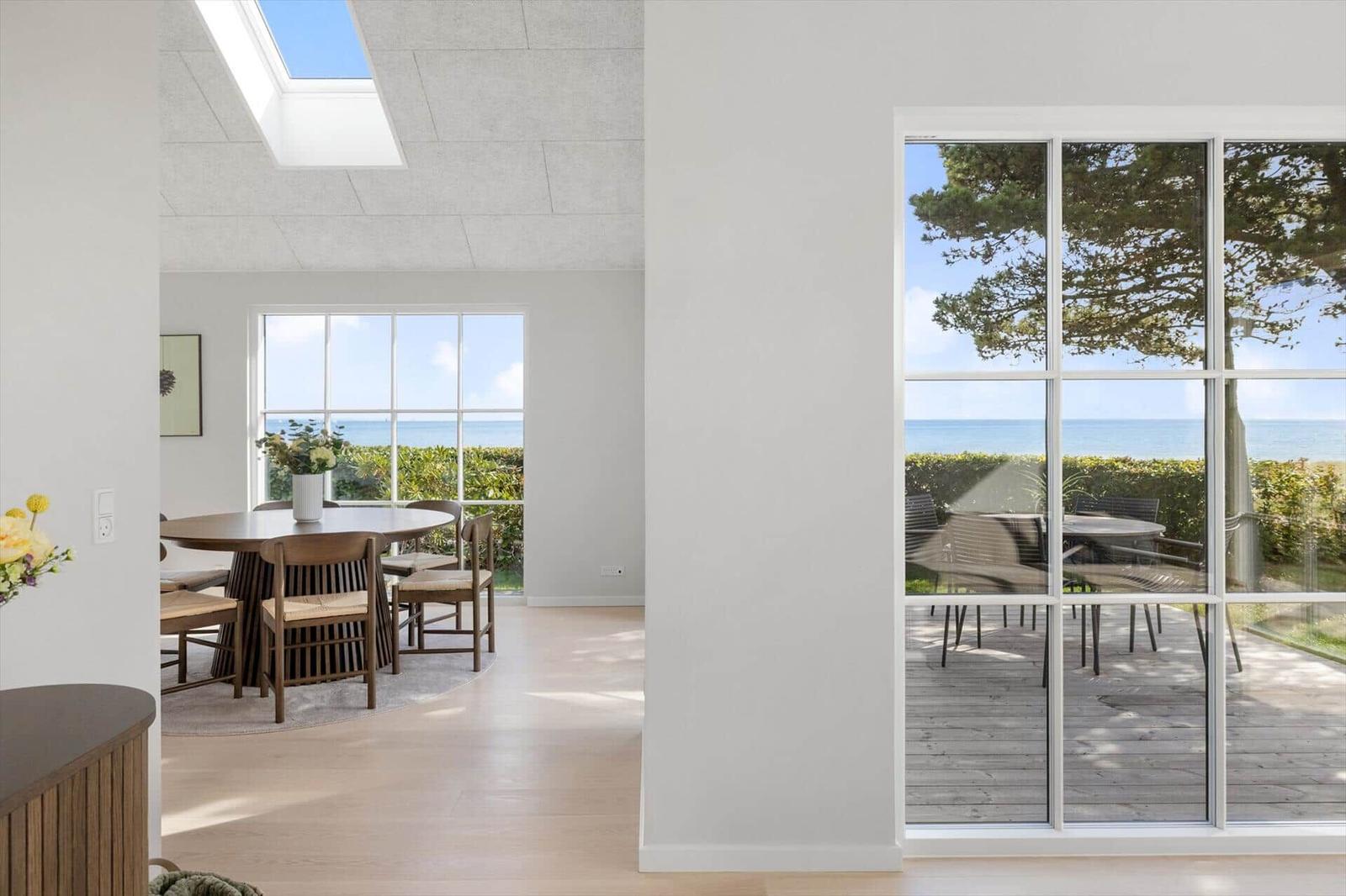 Durchgehendes Wohn- und Esszimmer mit Blick auf den Strand und Garten.