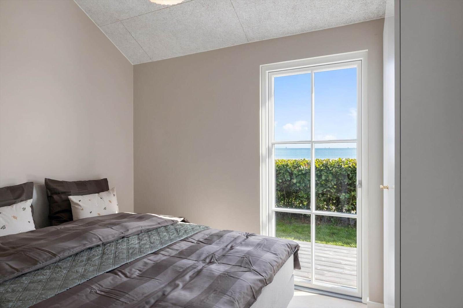 Schlafzimmer mit Blick auf das Meer durch eine Glastür.
