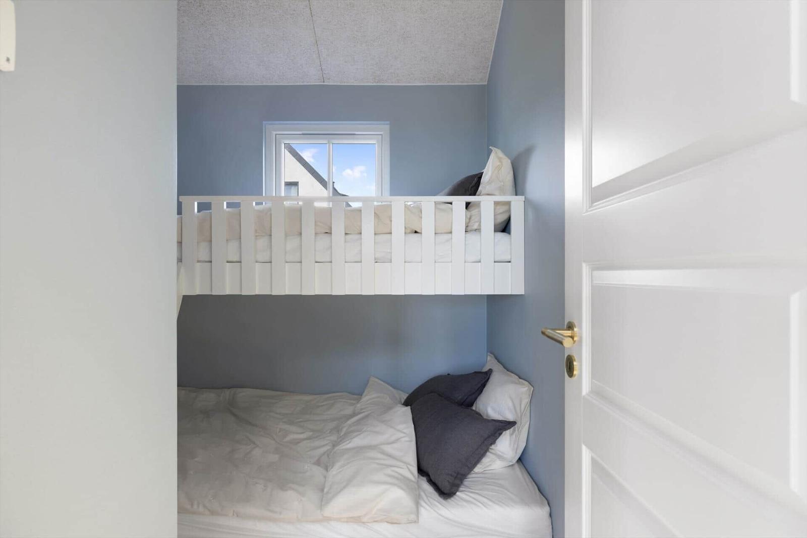 Ein Schlafzimmer mit einem hohen Bett und einem unteren Bett. Die Wände sind blau gestrichen.