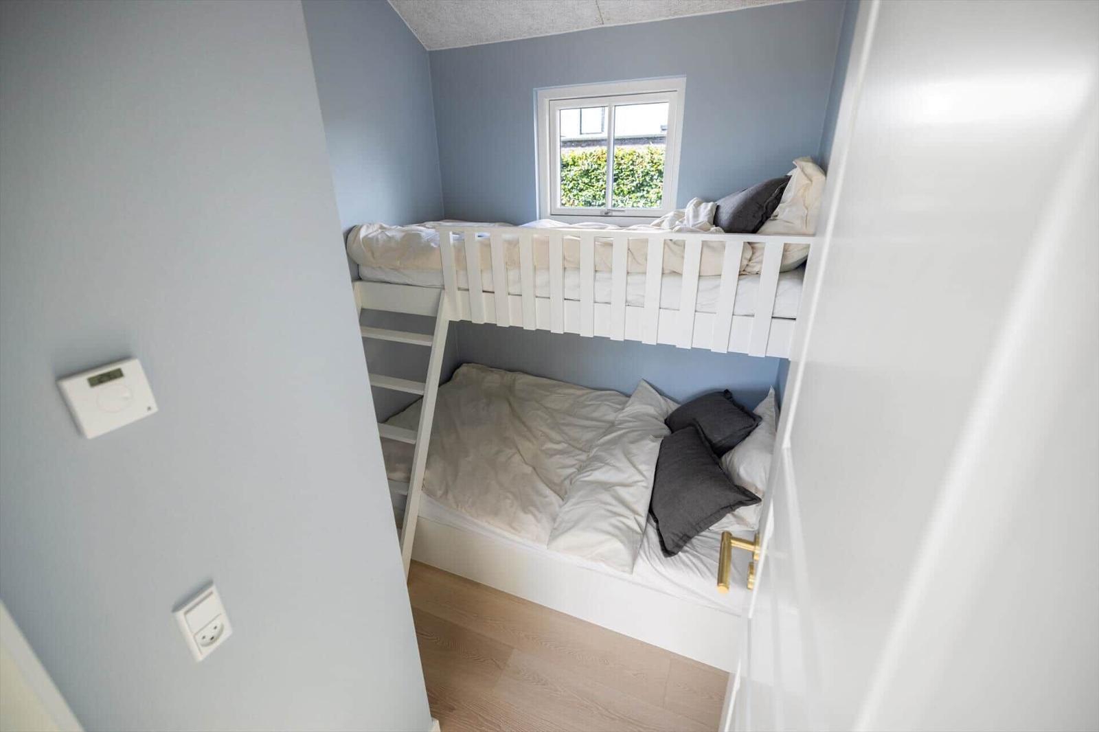 Zimmer mit Doppelstockbett, Fenster und Holzboden.