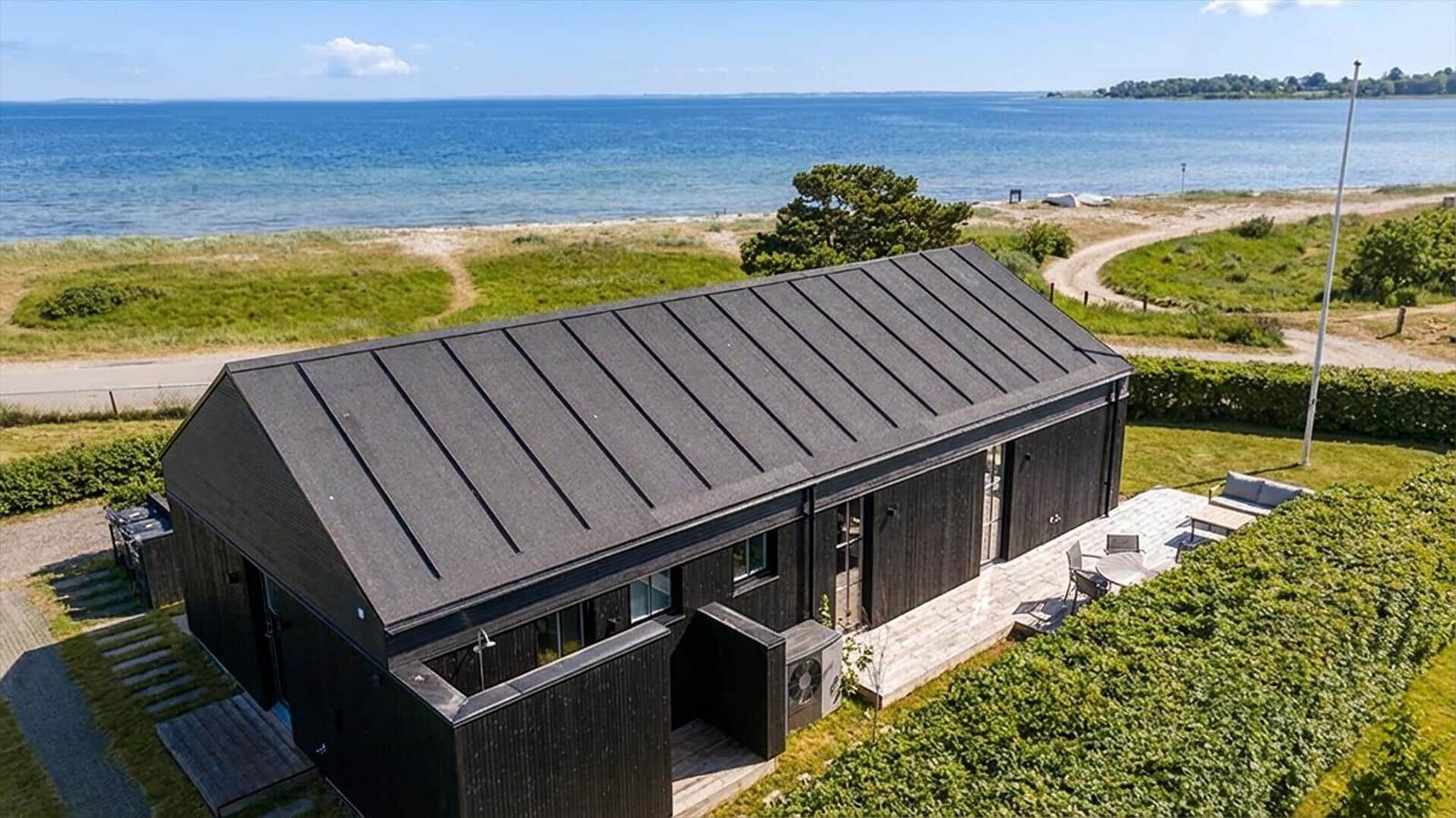Modernes Haus mit Terrasse und Meerblick. Umgeben von Grünflächen und Strand.