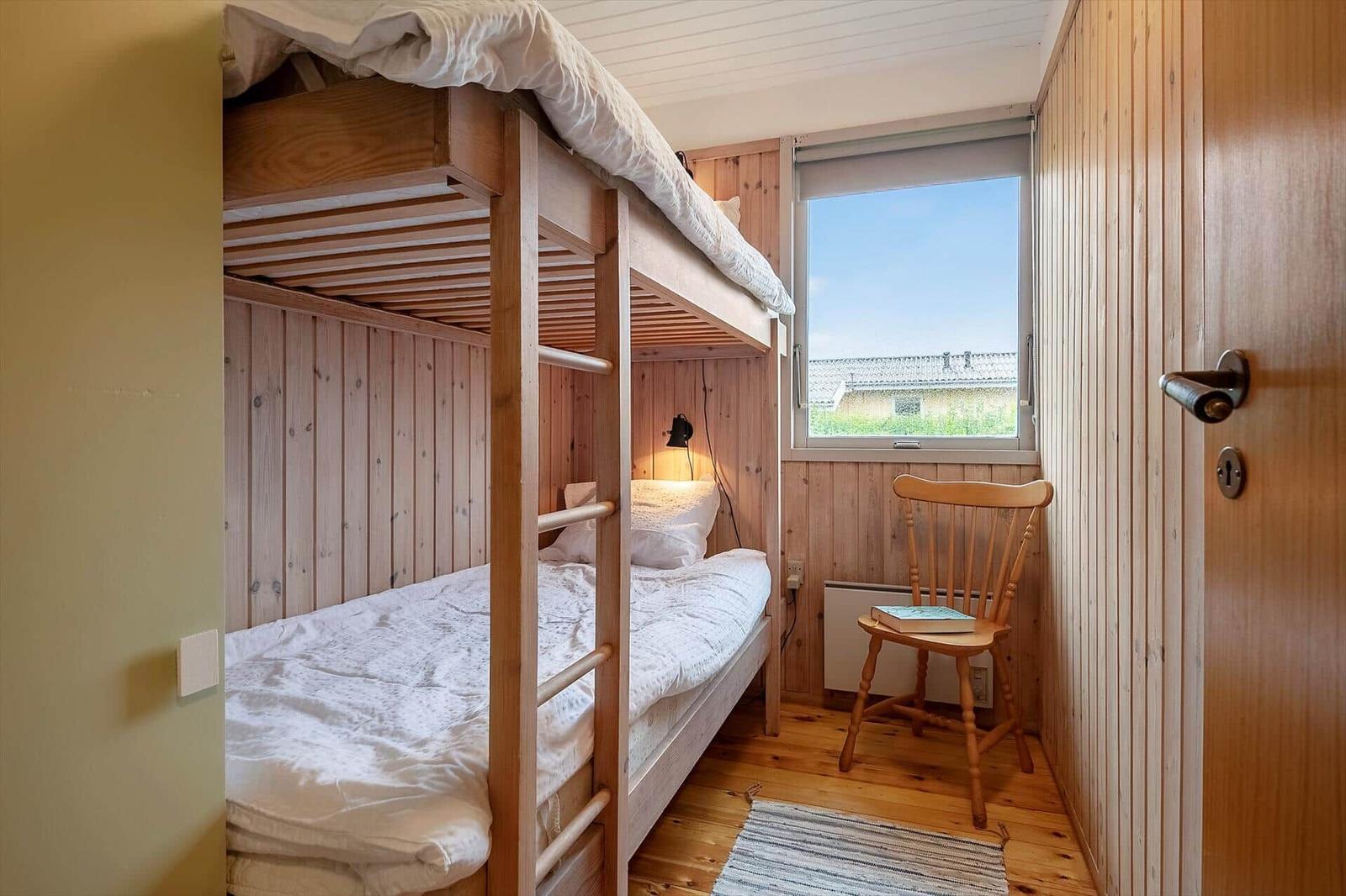 Zimmer mit Doppelstockbett, Holzwand und Fenster mit Blick.