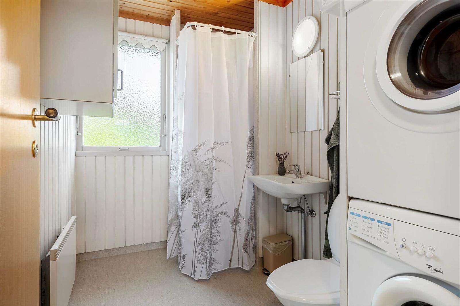 Badezimmer mit Dusche, Waschbecken und Waschmaschine