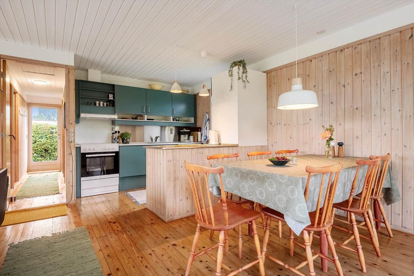 Küche mit Essbereich, Holzwand und Küchentisch mit Stühlen.