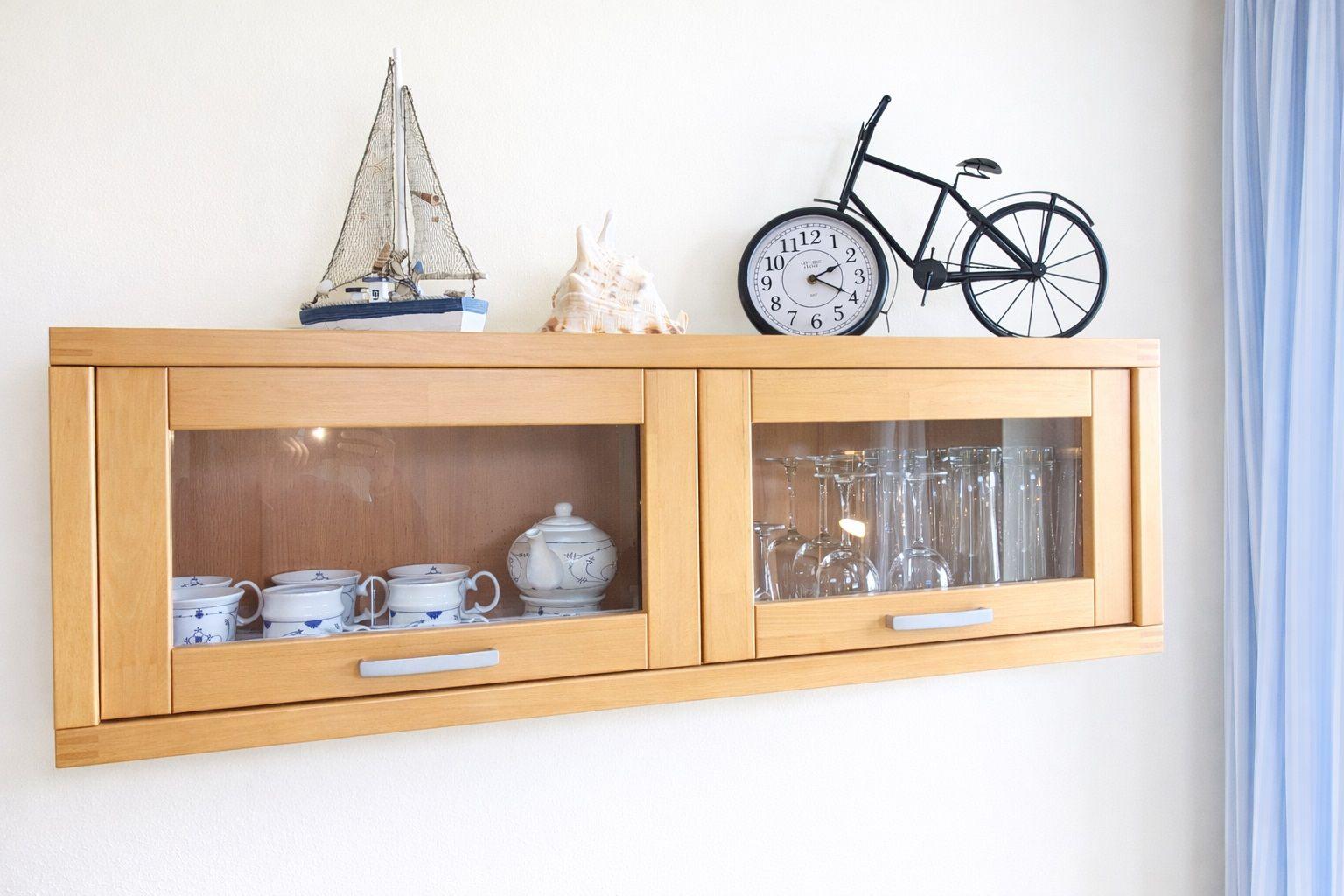 Holzschrank mit Glasfronten, darauf Segelboot, Muschel und Fahrraduhr