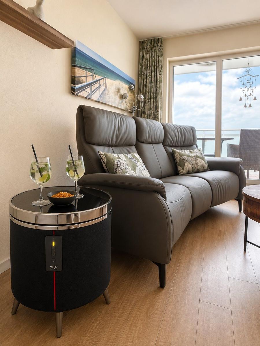 Gray leather sofa with cushions, table with drinks, view of balcony.