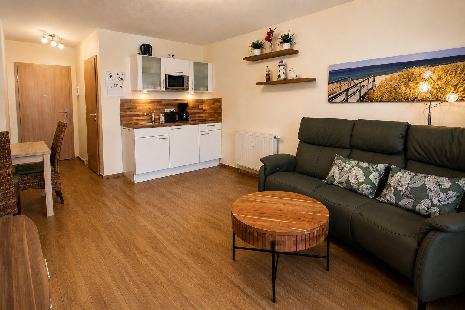 Living area with sofa, coffee table, and kitchen in the background.