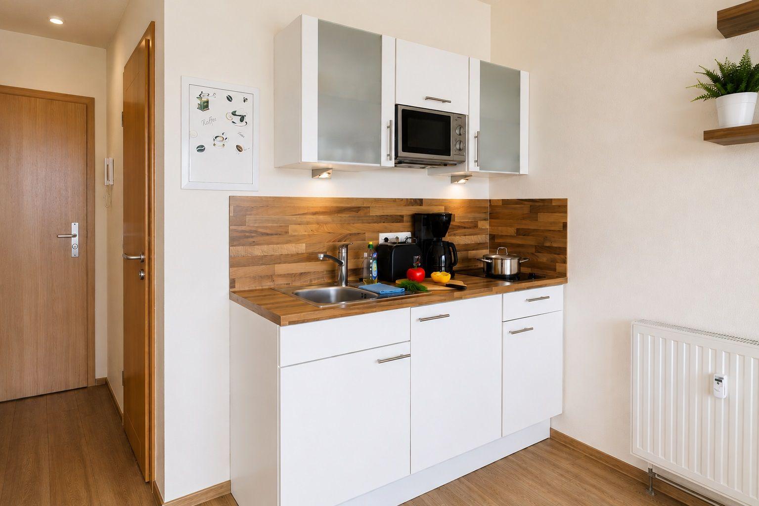 Kitchen with white cabinets, wooden backsplash, and built-in microwave.