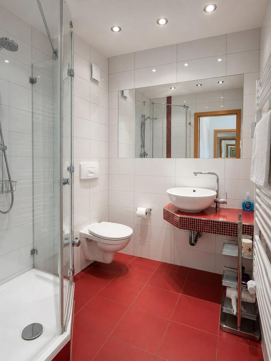 Bathroom with shower, toilet, and sink on red mosaic