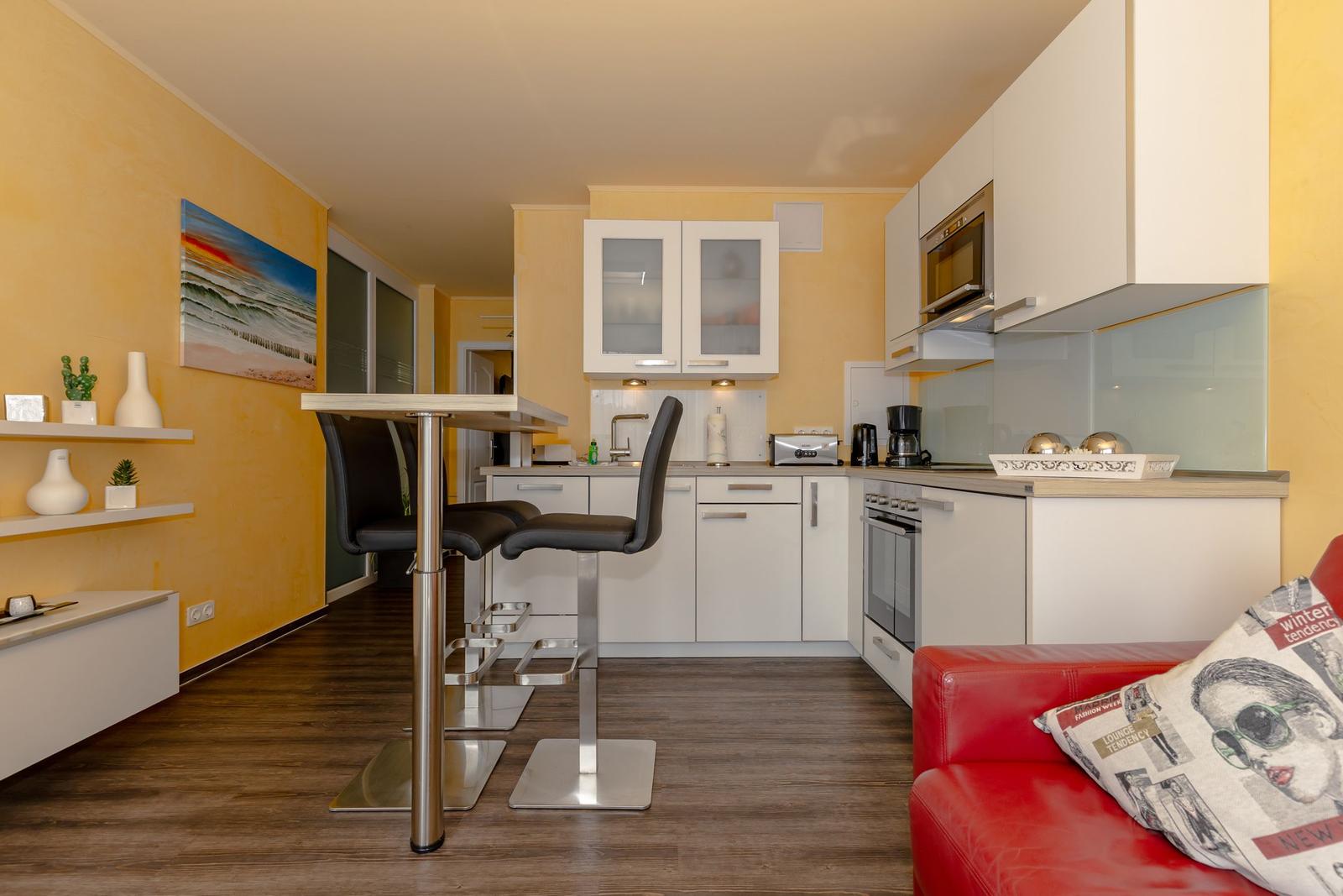 Küche mit Barhocker, rotem Sofa und gelben Wänden.
