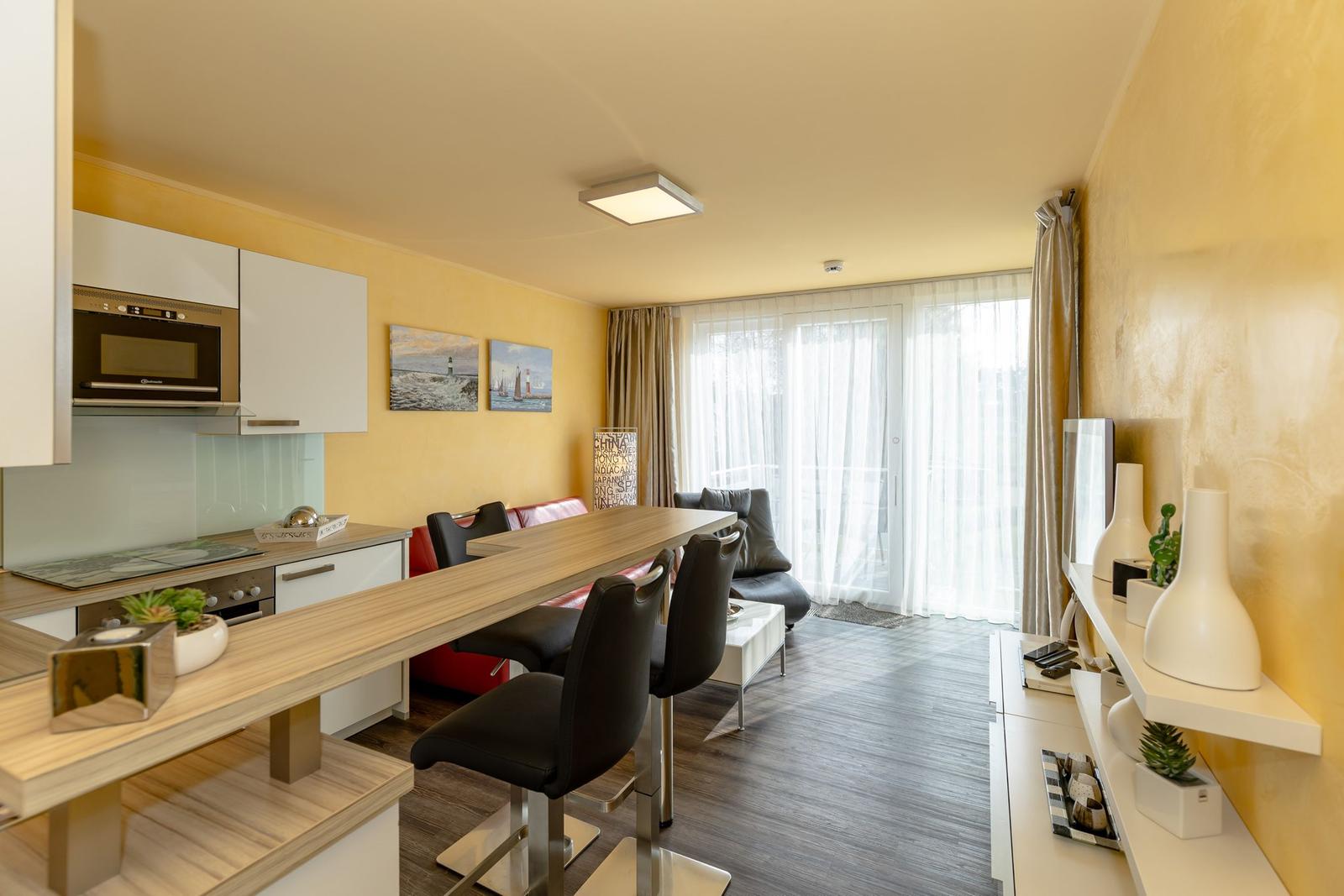 Küche mit Essbereich, Wohnzimmer und Balkon mit Türen.