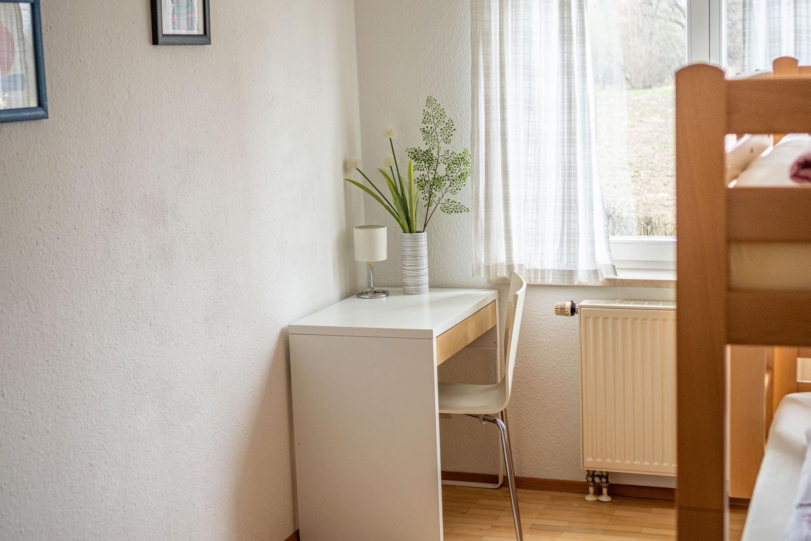 Schreibtisch mit Lampe und Pflanze neben Fenster mit Vorhang