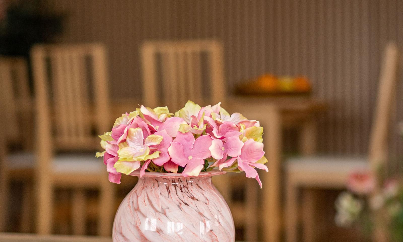 Ein Vasenarrangement mit rosa und gelben Hortensien auf einem Tisch.