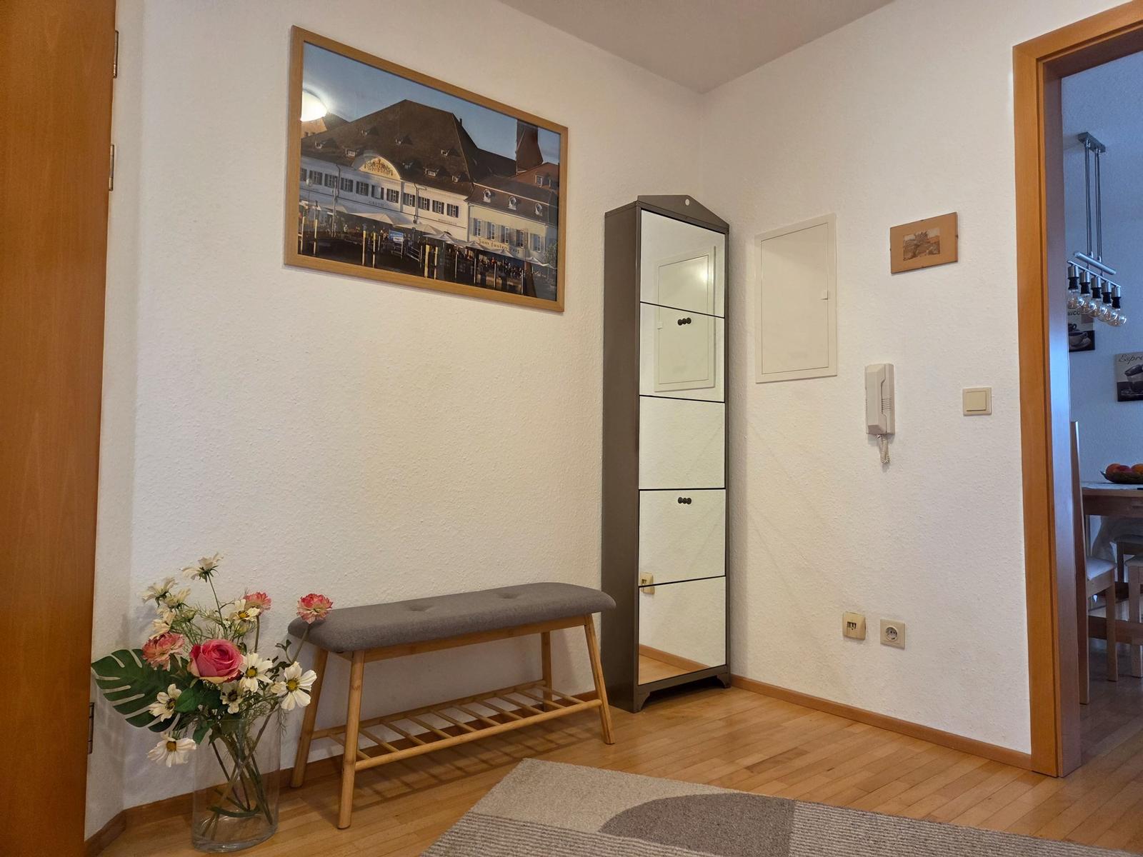 Eingangsbereich mit Bank, Blumen und Schrank. Durchgang in die Küche.