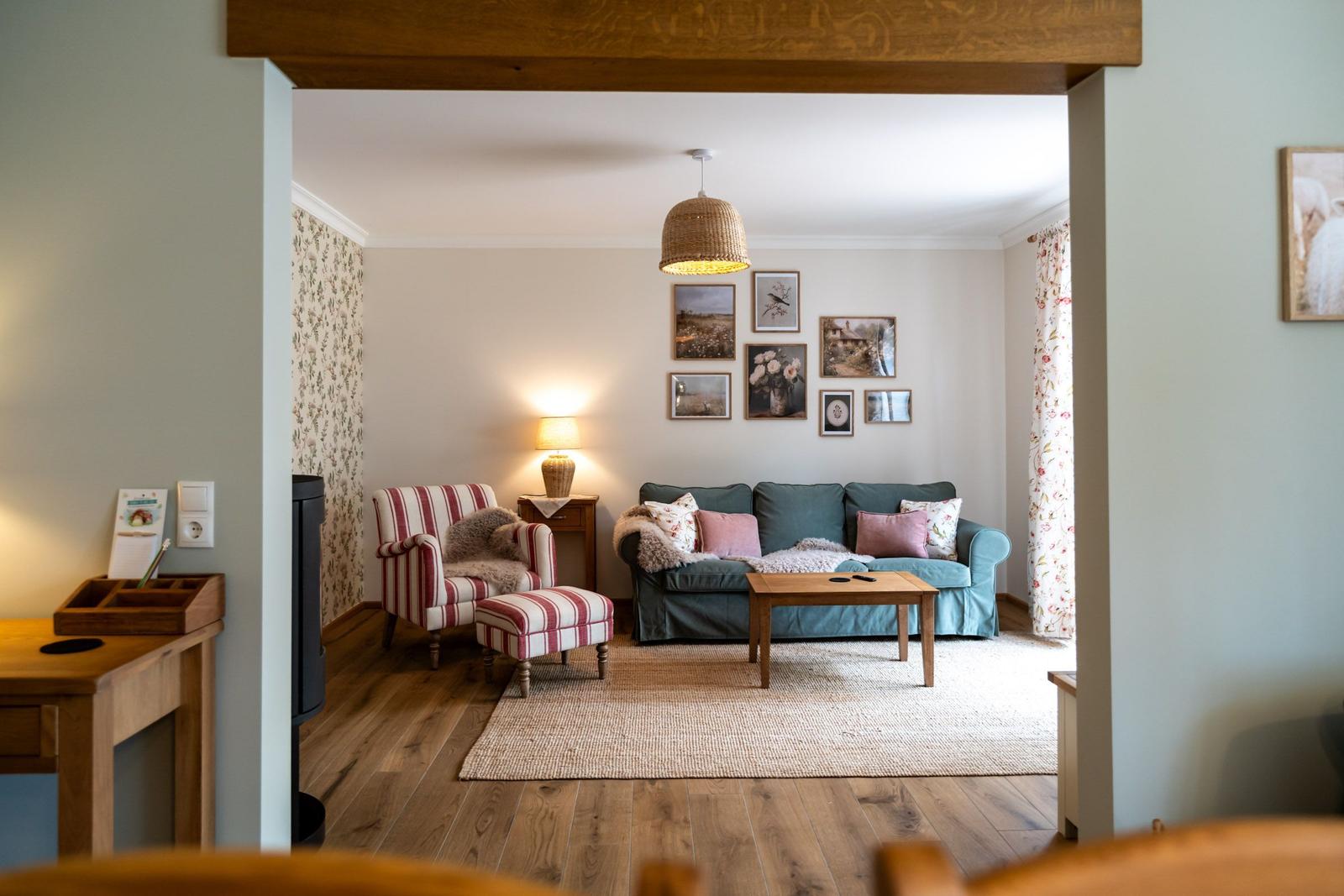 Wohnzimmer mit Sofa, Sessel, Tisch und Wandbildern.