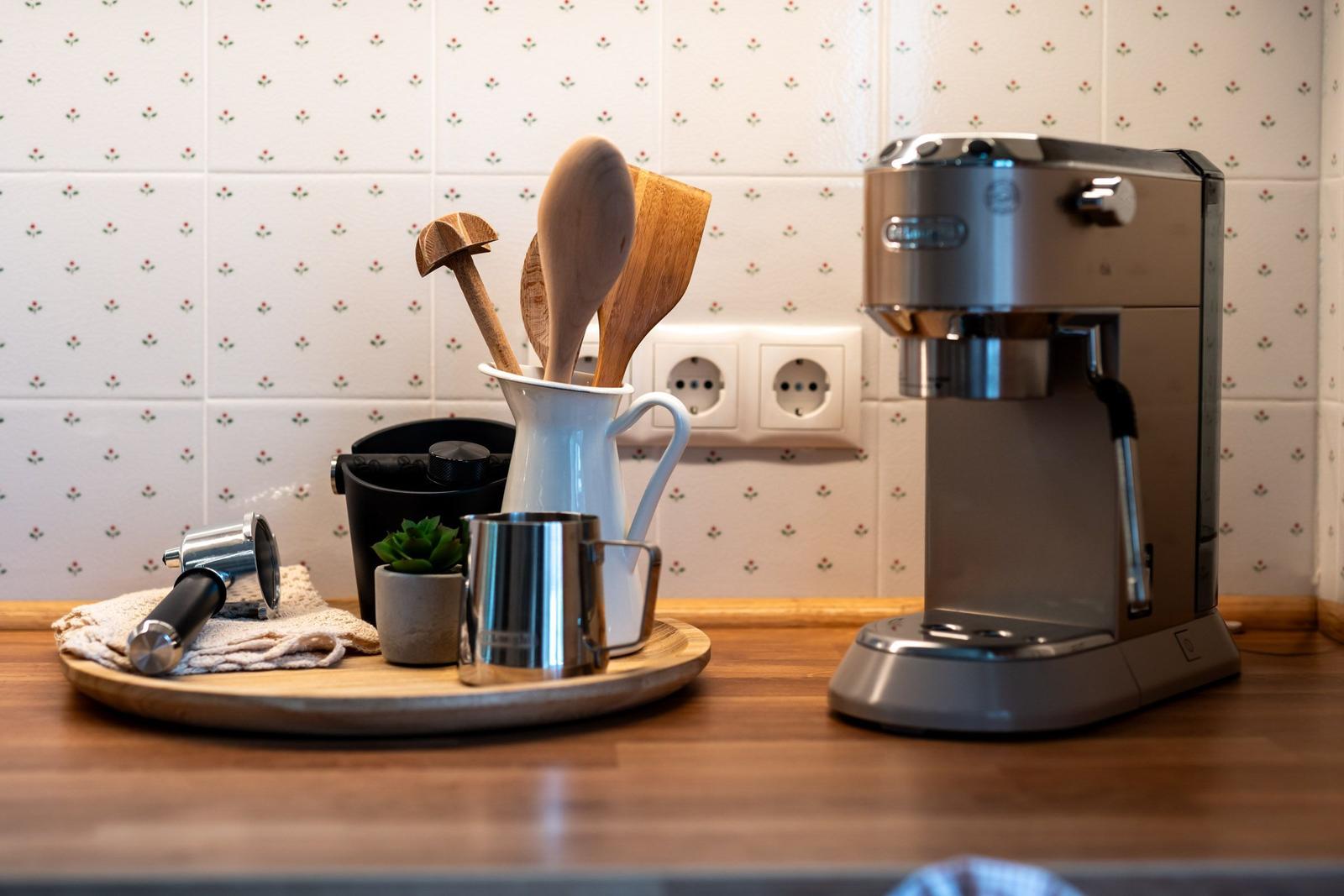 Küchenarbeitsfläche mit Kaffeemaschine, Holzlöffeln und Pflanze.