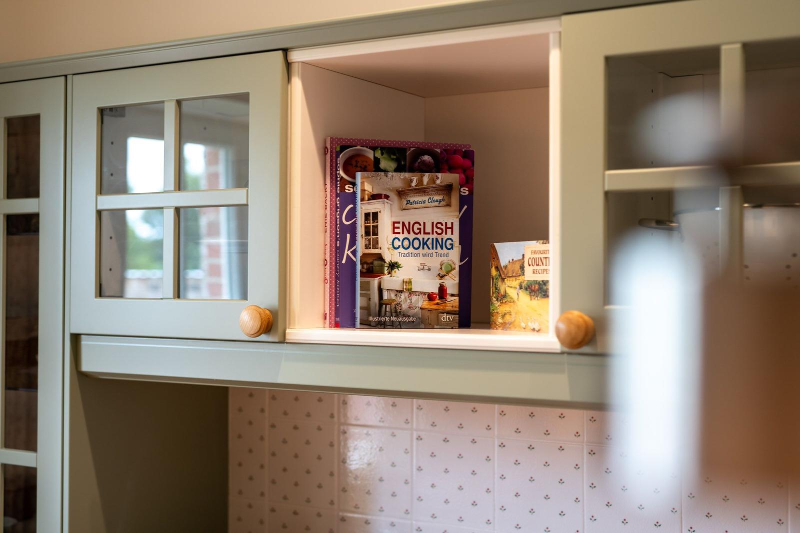 Küchenregal mit Kochbüchern und Holzgriffen