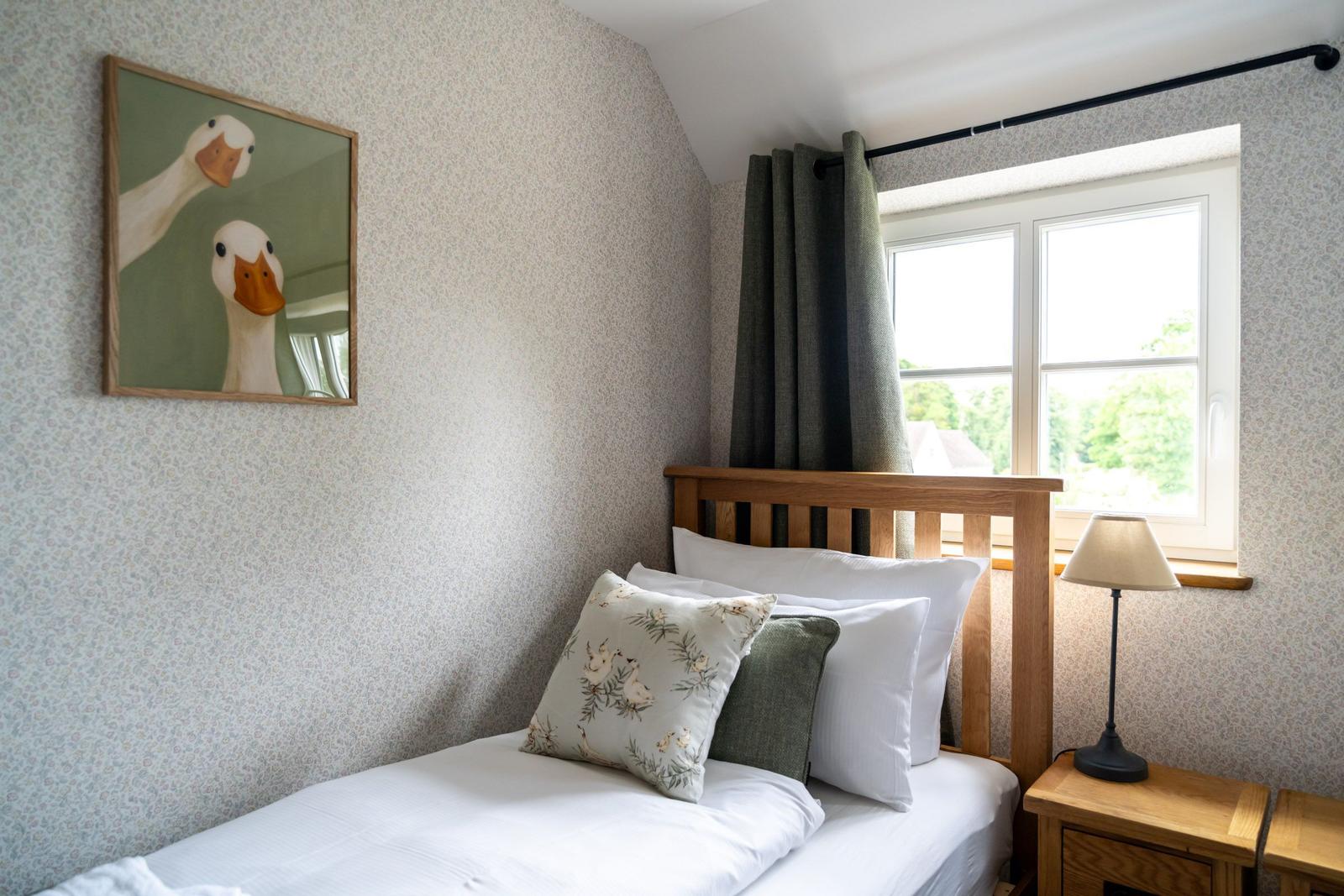 Ein Schlafzimmer mit Bett, Fenster und Wandbild von Enten.