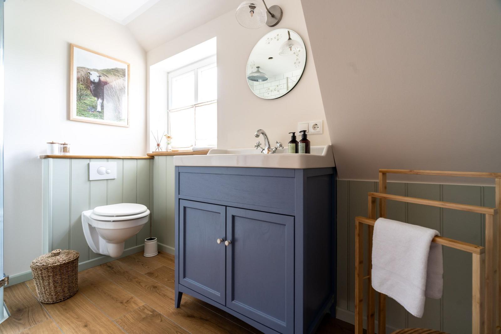 Badezimmer mit blauem Waschbeckenunterschrank, Spiegel und Toilette.