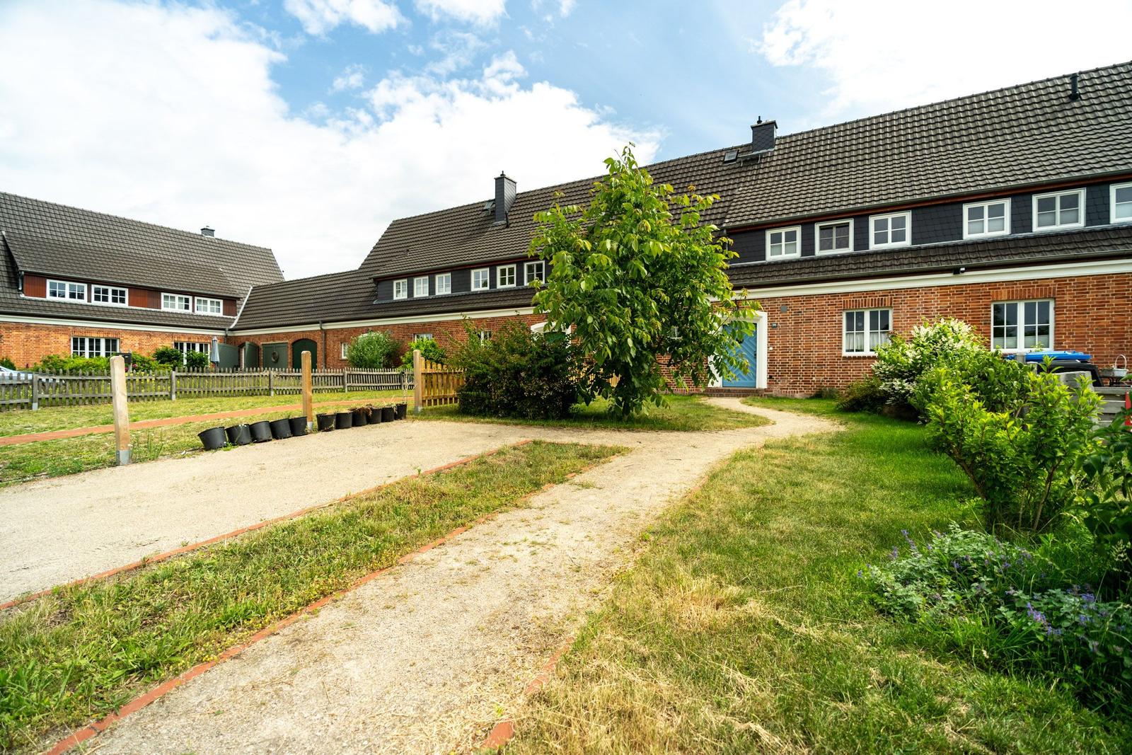 Roter Backsteinbau mit Gartentor und gepflastertem Weg.