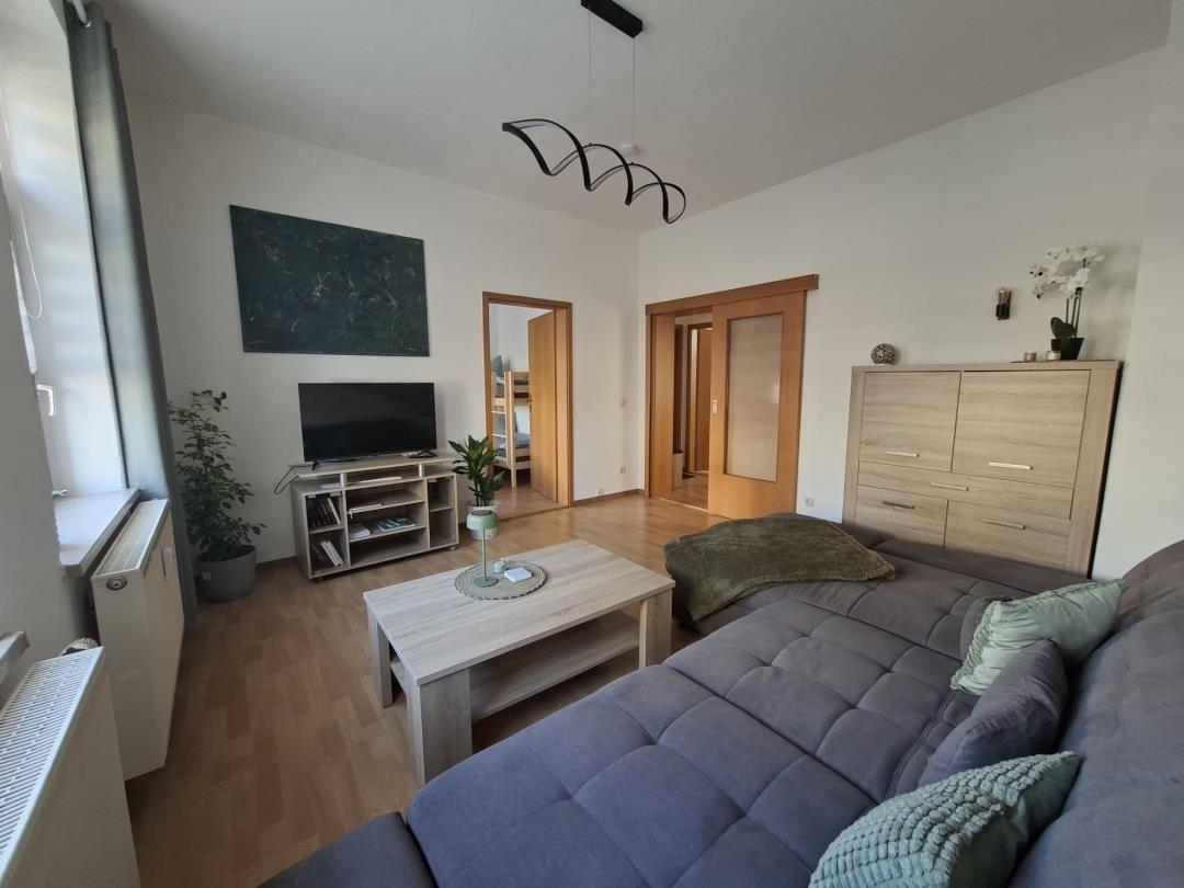 Living room with sofa, coffee table, TV, and wooden floor.