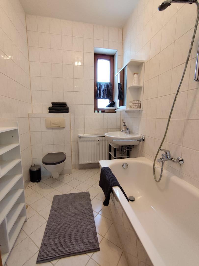 Bathroom with bathtub, sink, toilet, and window.