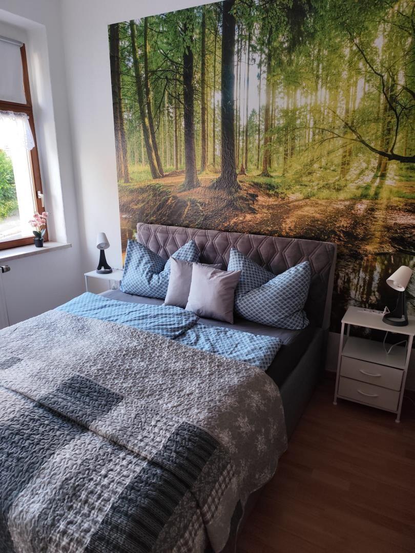 Bedroom with bed, nightstands, and forest wall mural.