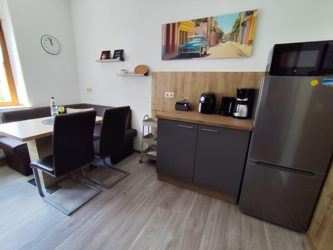 Kitchen with refrigerator, microwave, and dining area with table and chairs.