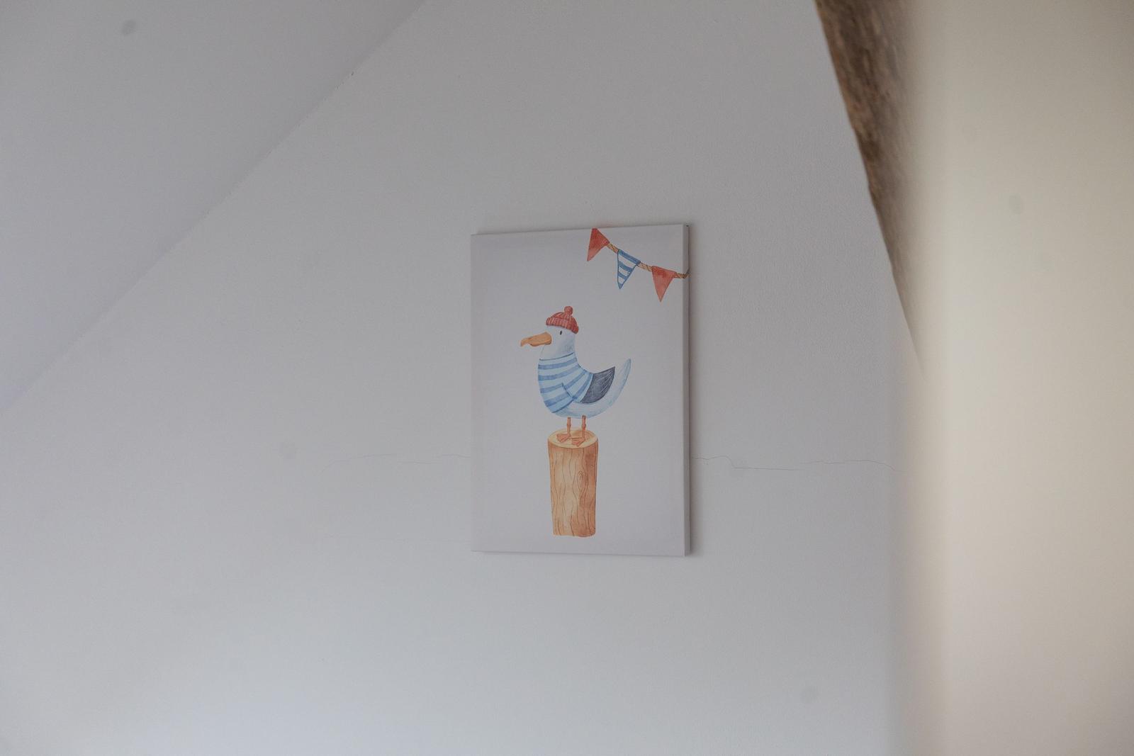 Ein Bild mit einer Möwe in einem gestreiften Hemd und einer Mütze hängt an der Wand.