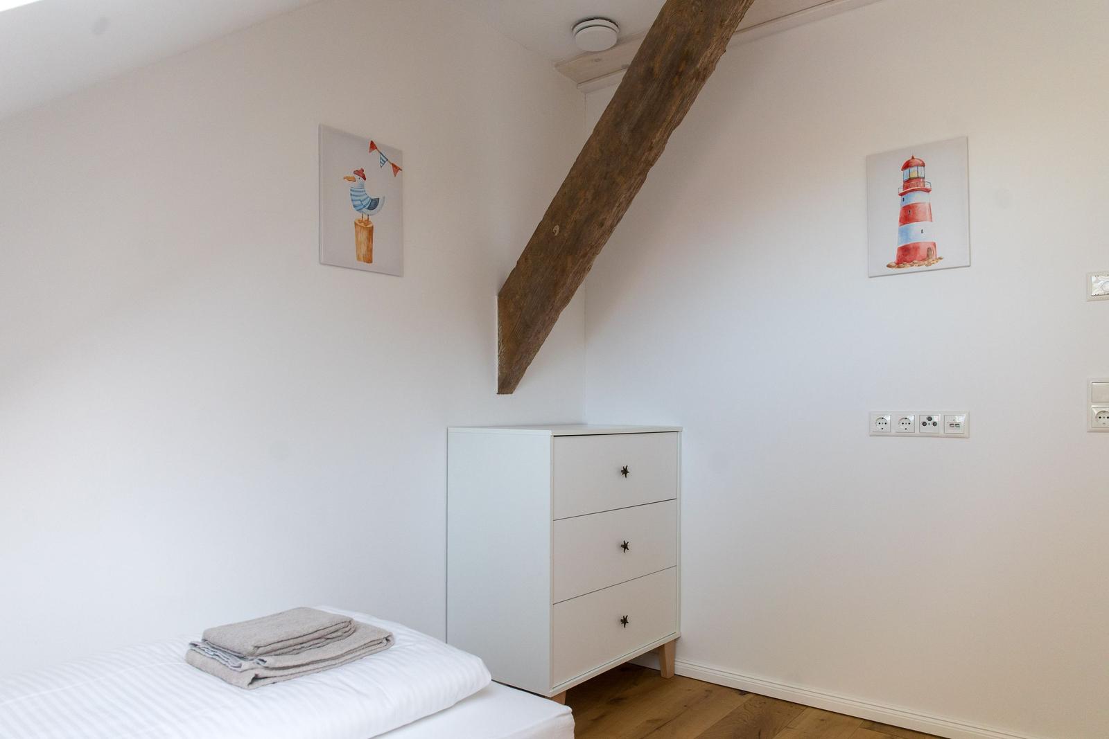 Schlafzimmer mit weißem Schrank, Bett und Holzbalken an der Wand.