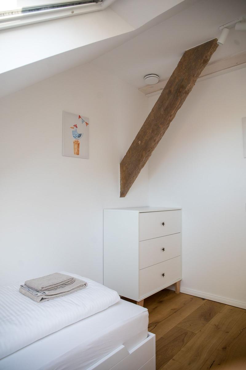 Schlafzimmer mit Bett, Kleiderschrank und Holzbalken an der Decke.