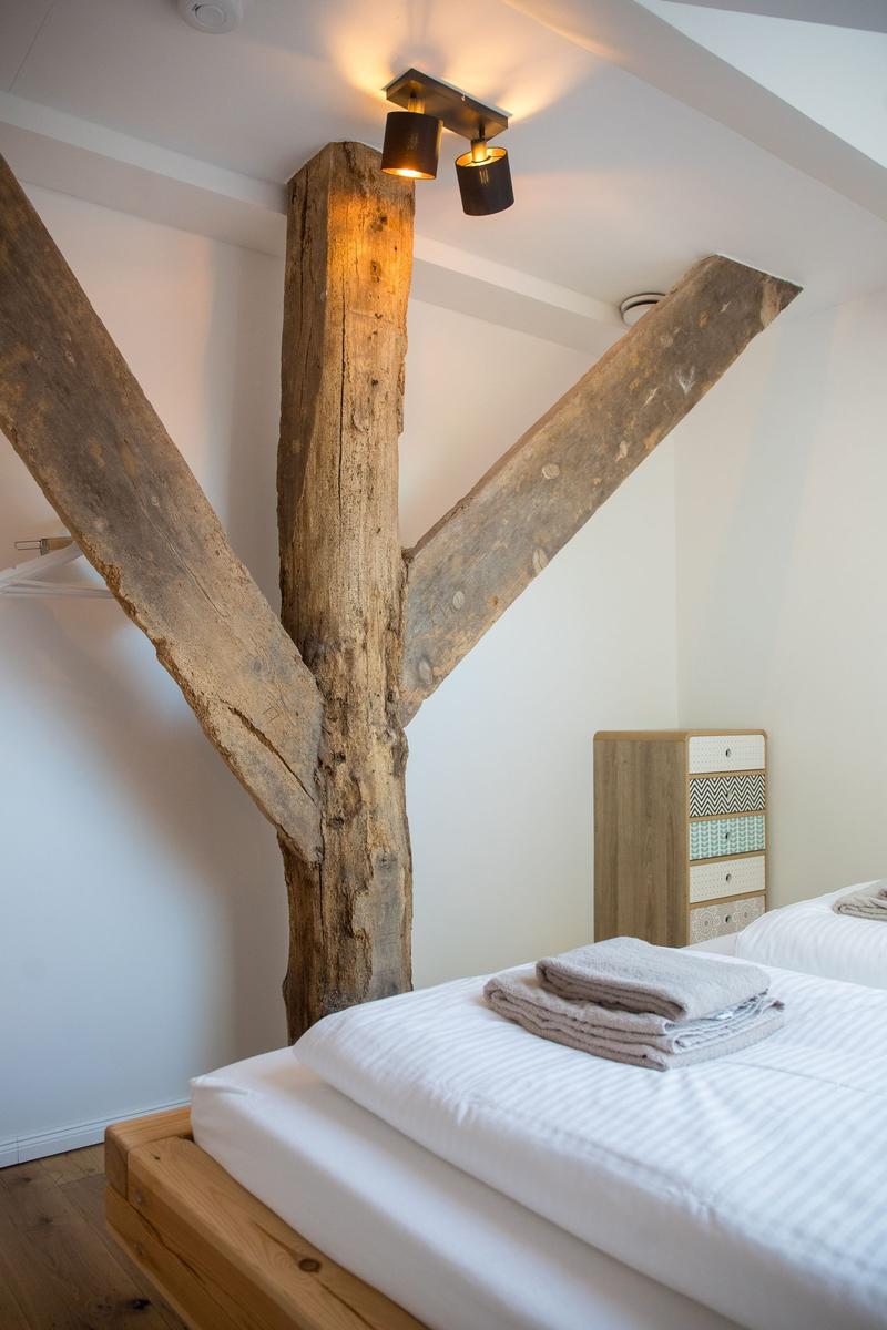 Schlafzimmer mit rustikalem Holzrahmen und Bett mit weißer Bettwäsche.