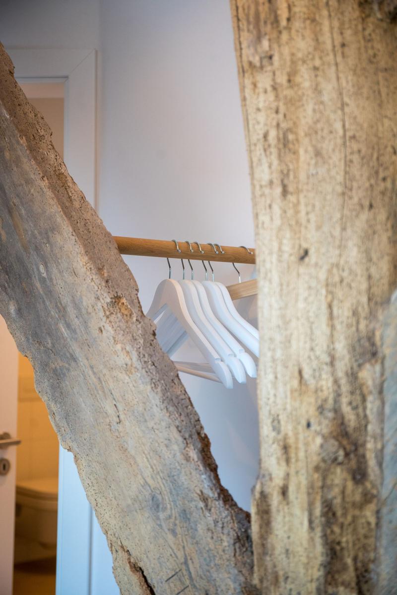 Kleiderständer mit weißen Haken zwischen rustikalen Holzelementen.