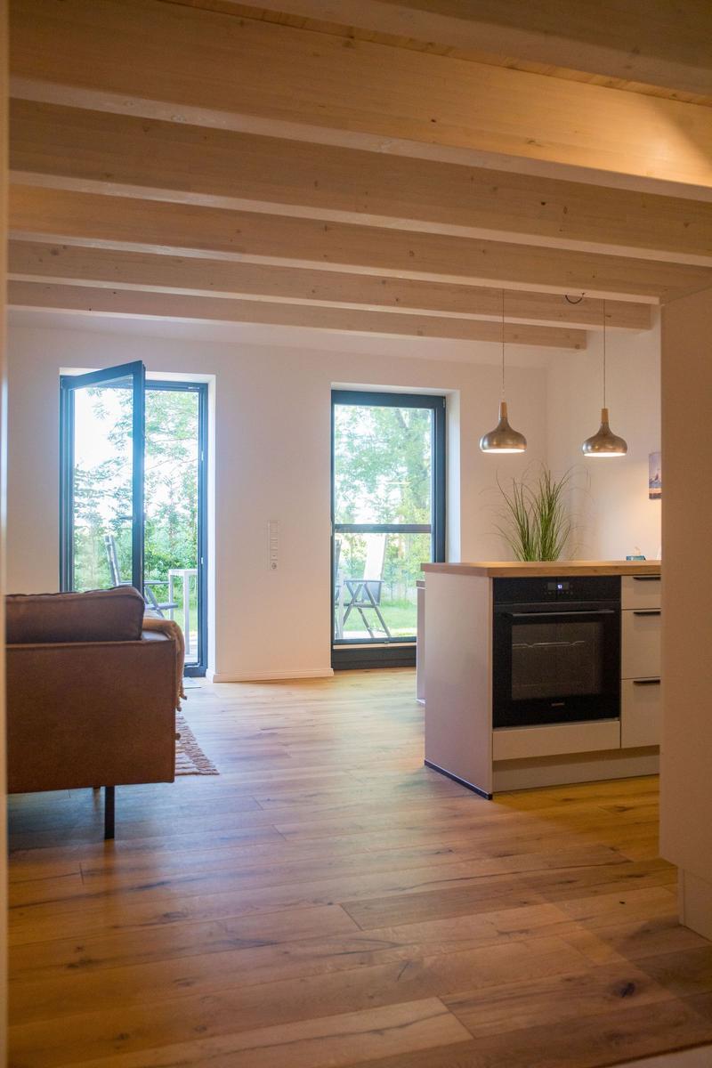 Wohnbereich mit Holzboden, offener Küche und Blick auf den Garten.