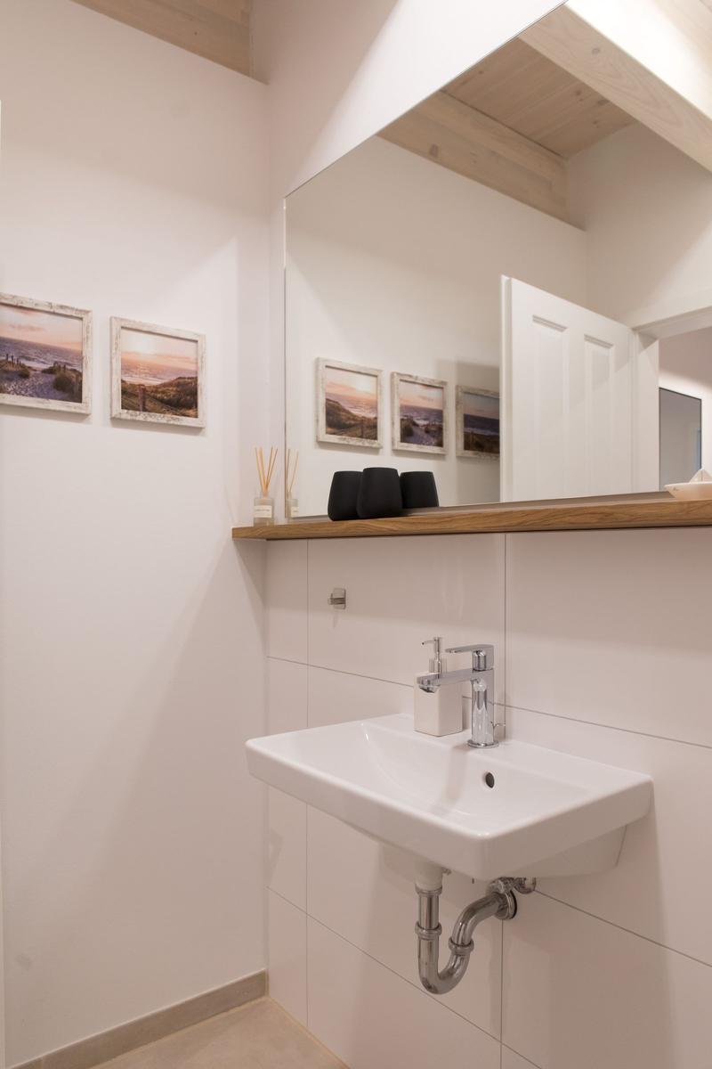 Waschbecken mit Spiegel, Holzregal und Wandbildern