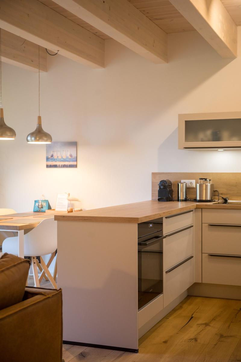 Küche mit Holzoberfläche, integriertem Backofen und Essbereich mit Tisch und Stühlen.