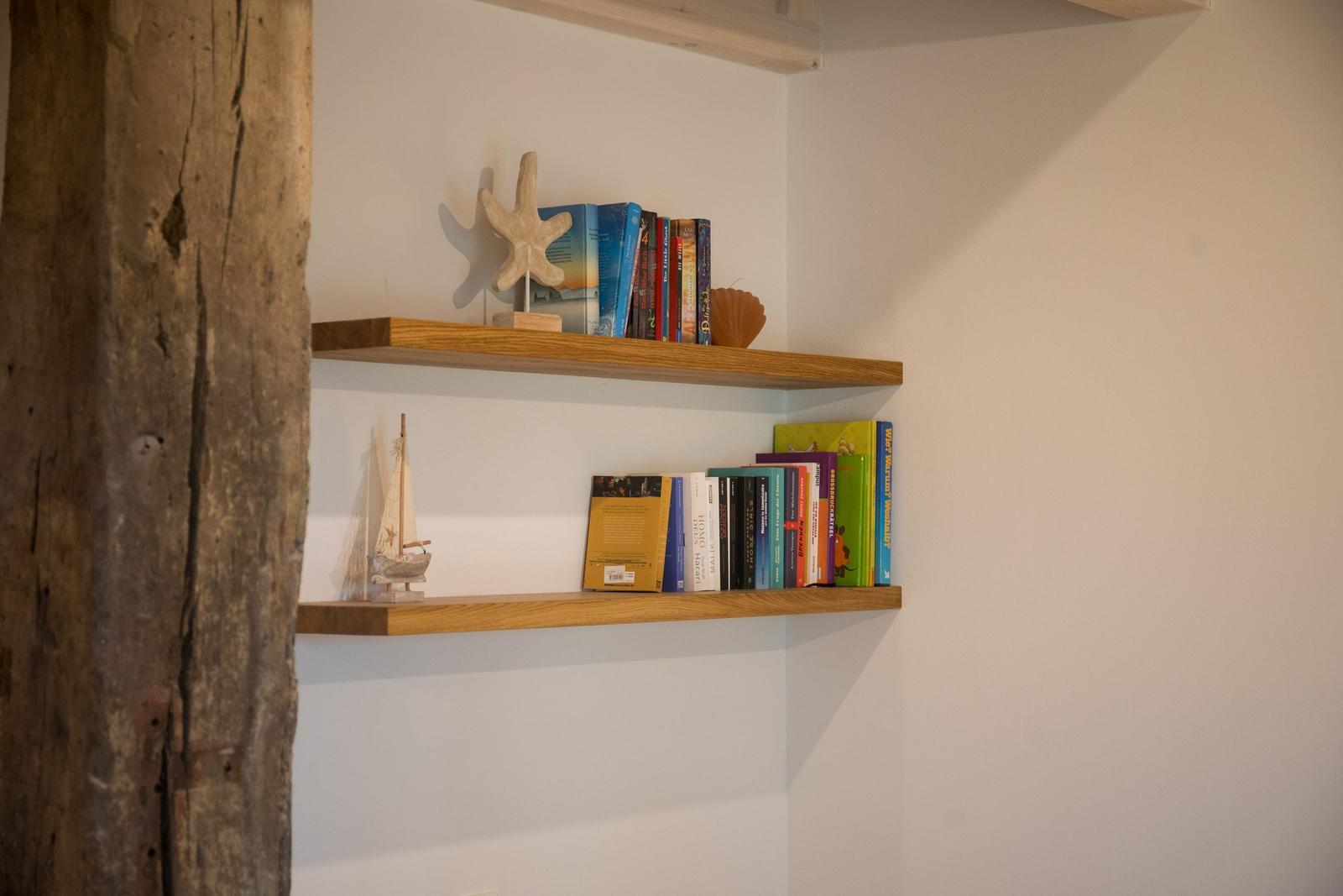Zwei Holzregale an der Wand mit Büchern und Meeresdekoration.