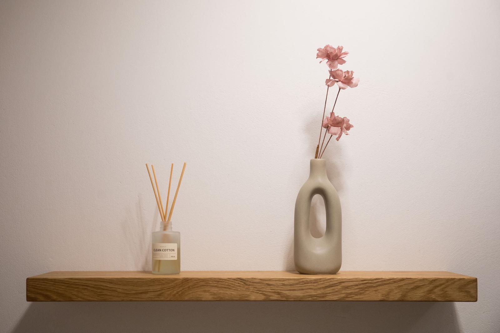 Holzregal mit Duftflasche und Vasenblumen